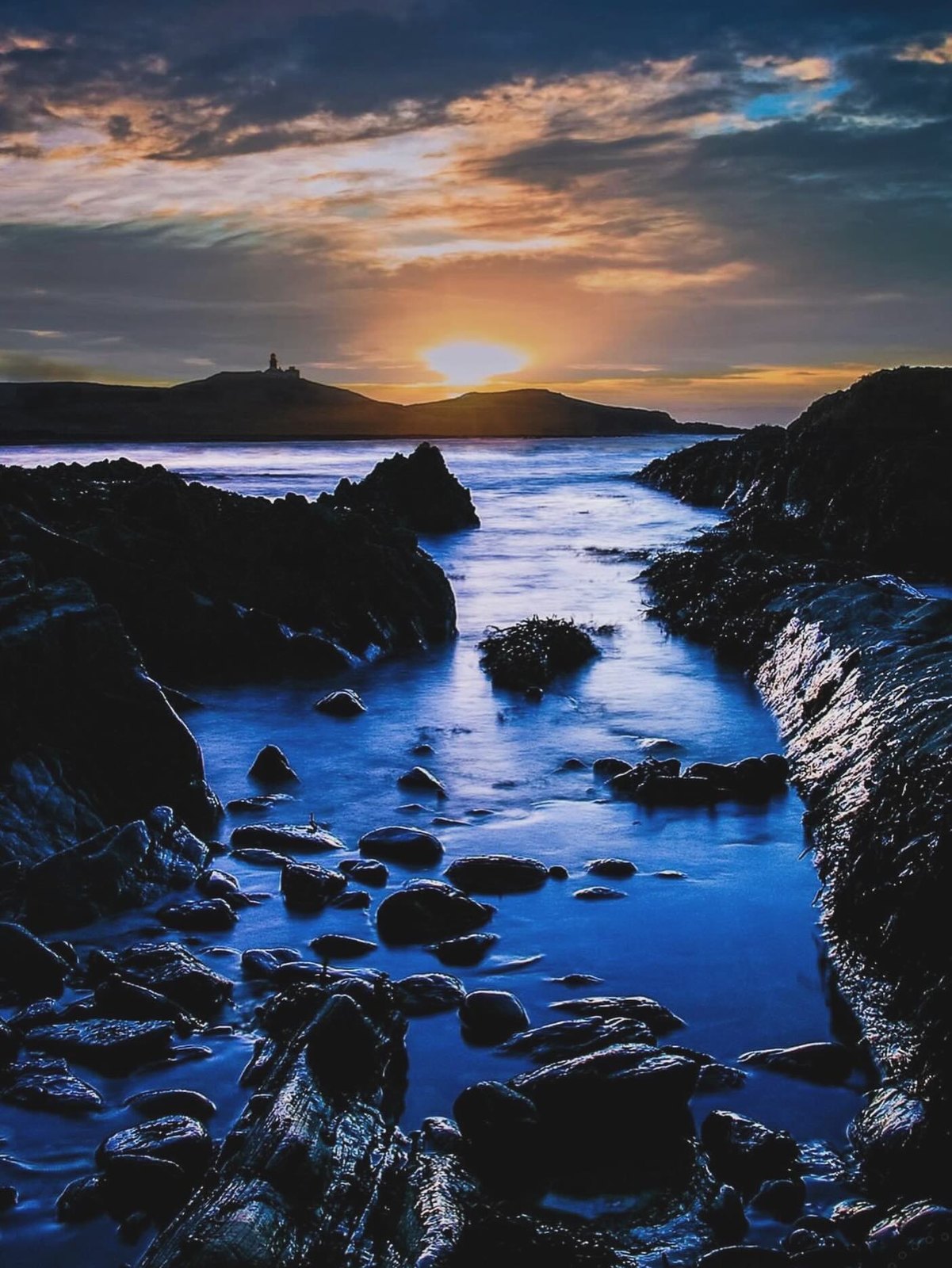 First light over a stony beach at Ballycotton on the Cork coast, the sea flat and cold at sunrise.