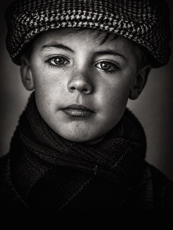 Black and white portrait of a young boy in a flat cap, a face that could belong to another century.