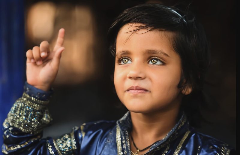 Portrait of a young child in India, curiosity and innocence meeting the camera in soft light.