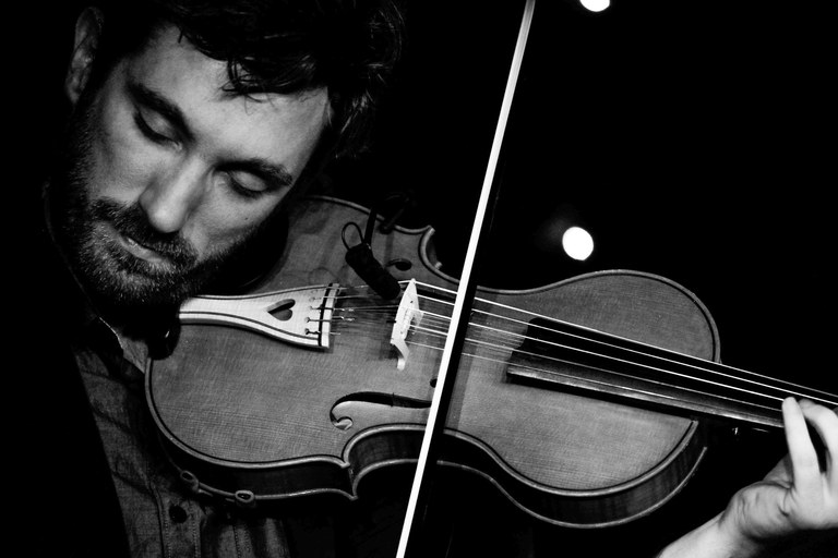 Black and white portrait of a fiddler, notes taking flight in shadowed light.