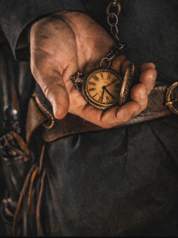 A weathered hand holding an old pocket watch, an echo of the gunslinger era of the American West.