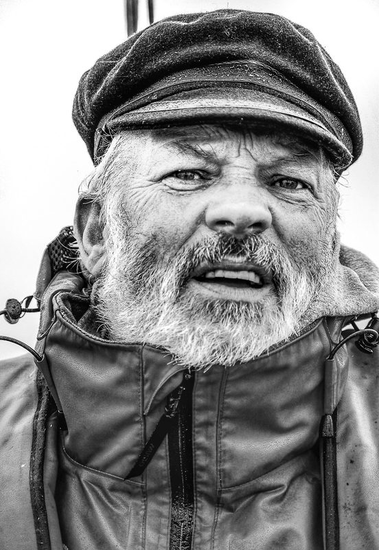 Portrait of a seasoned sailor, weathered hands and eyes of steel, every line etched by storms and spray.