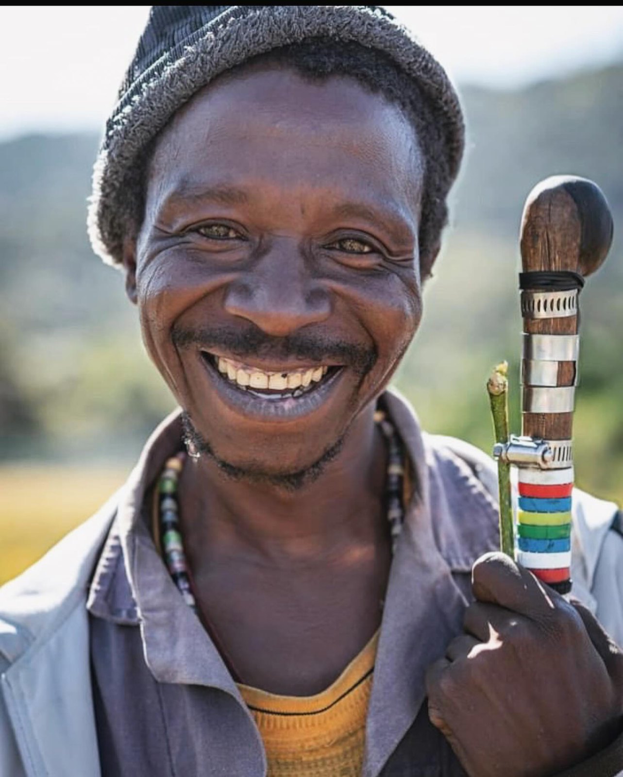 An elder leaning on a wooden staff in a quiet village where life moves at a human pace.