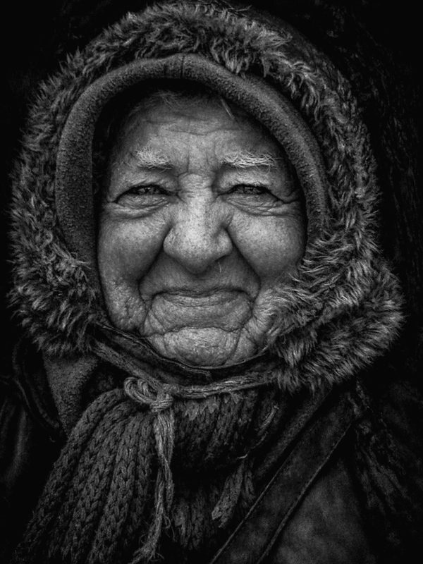 Black and white portrait of an elderly woman in a fur hood, her face a map of a long life.